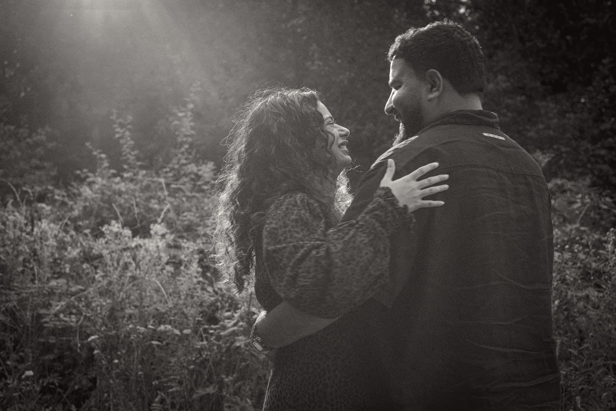 Ishmeet laughing up at Talwinder, her hand on his shoulder, the low sun behind them, in black and white